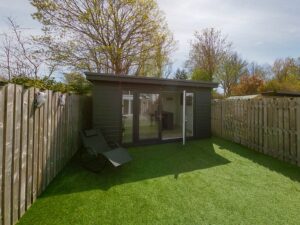 Grey composite garden room on artificial grass.